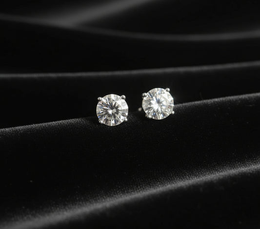Diamond stud earrings on a black fabric background
