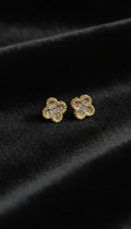Gold clover-shaped earrings on a black background