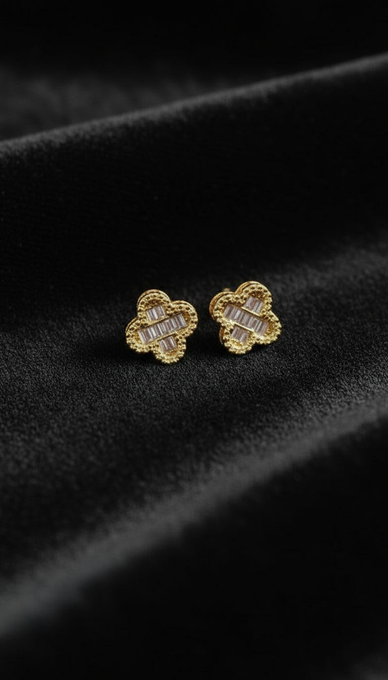 Gold clover-shaped earrings on a black background
