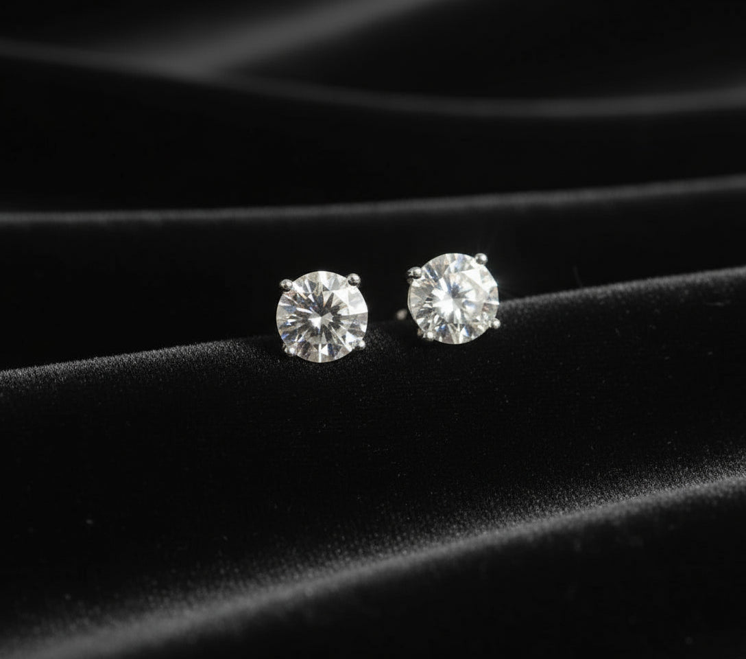 Diamond stud earrings on a black fabric background