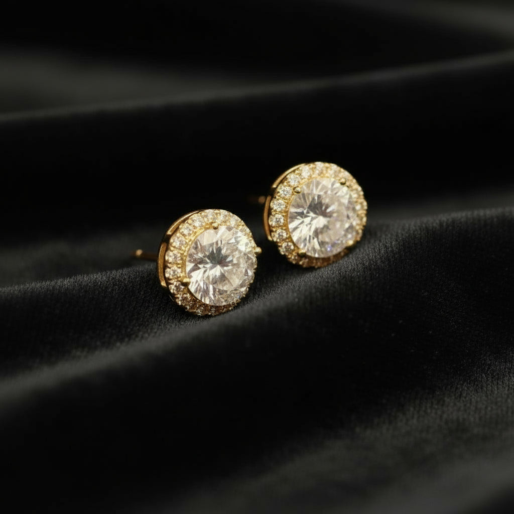 Gold earrings with clear gemstones on a black velvet background