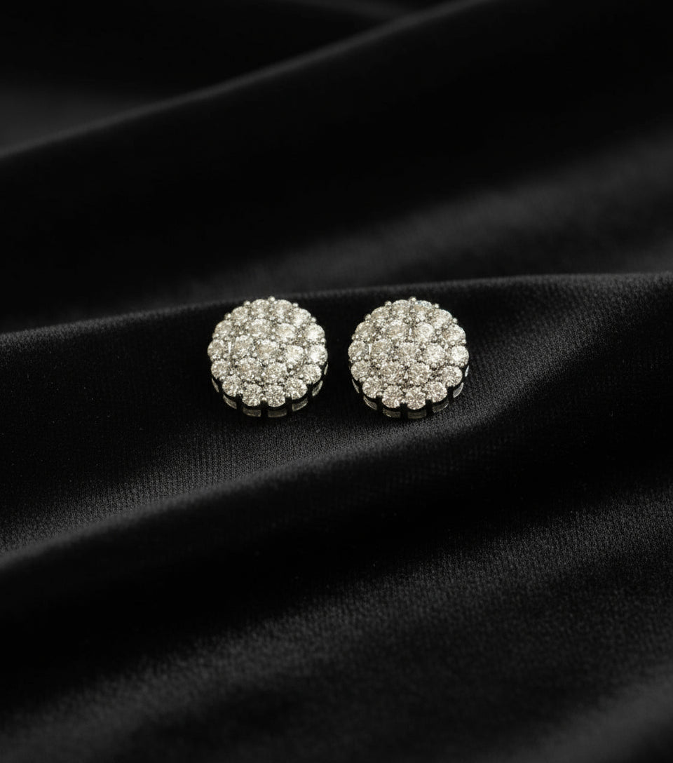 Pair of silver stud earrings with clear stones on a black fabric background