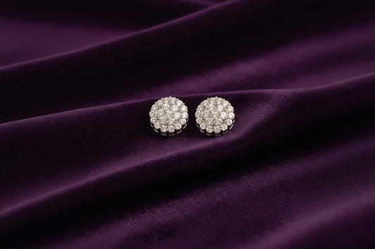 Pair of silver stud earrings with clear stones on a black fabric background